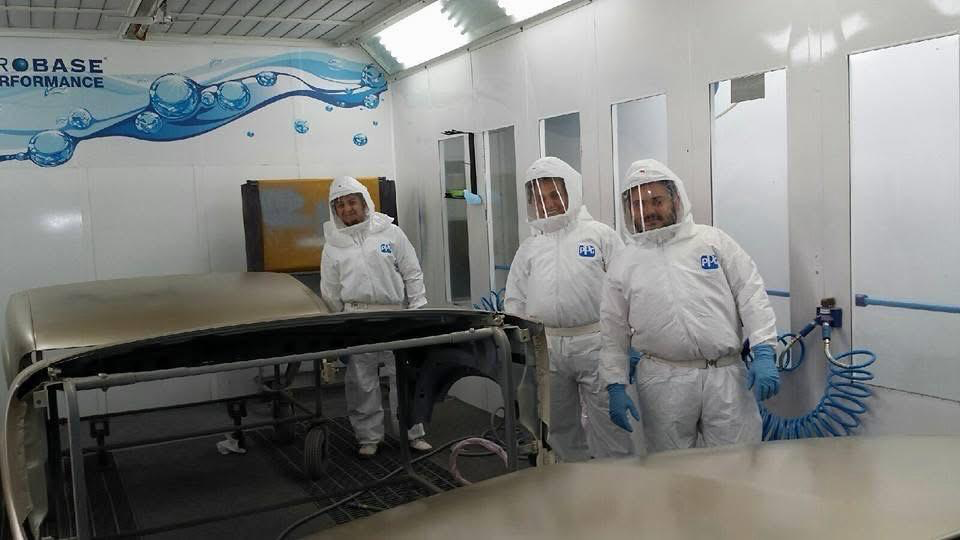 Jimmy's Auto Repair paint team standing in protective suits inside the paint booth